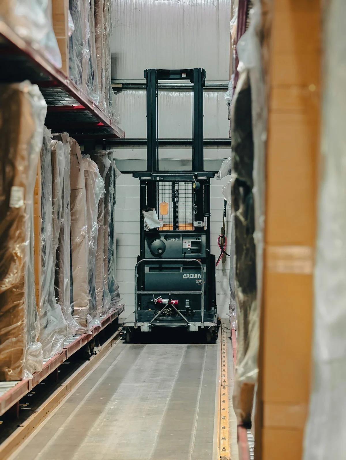 Real logistics reference photograph of warehouse racking, boxes, and pallet handling equipment.